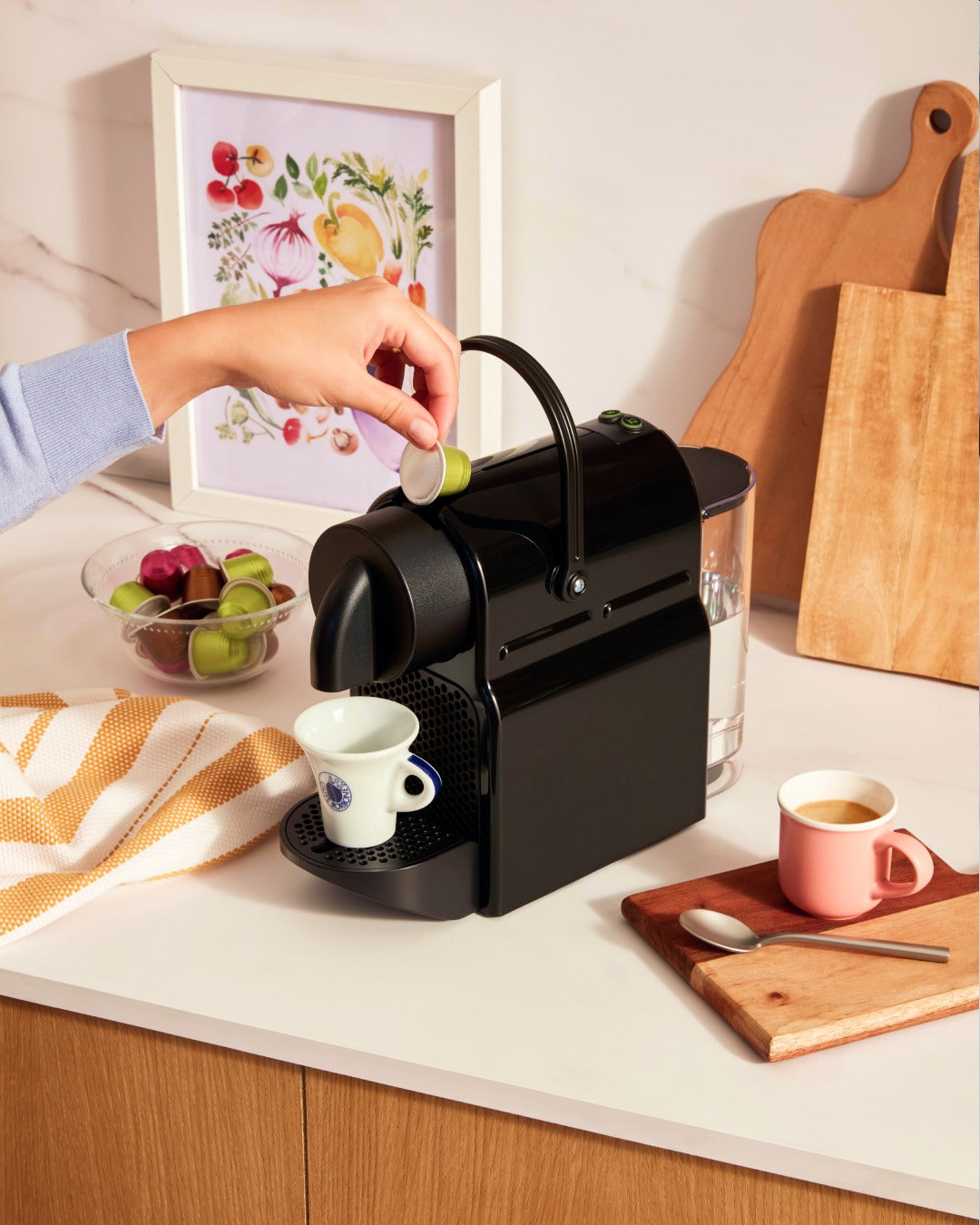 une femme mettant une capsule Nespresso dans une machine a café inissia Krups